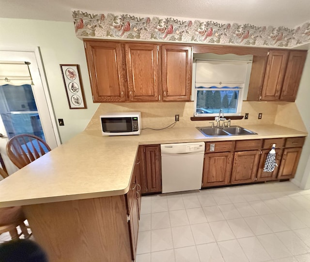 kitchen featuring kitchen peninsula, white appliances, and sink