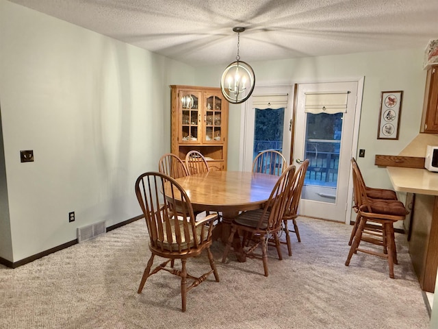 carpeted dining room featuring a textured ceiling and an inviting chandelier