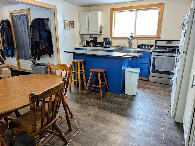 kitchen featuring sink, dark wood-type flooring, stainless steel range oven, a kitchen bar, and white cabinets