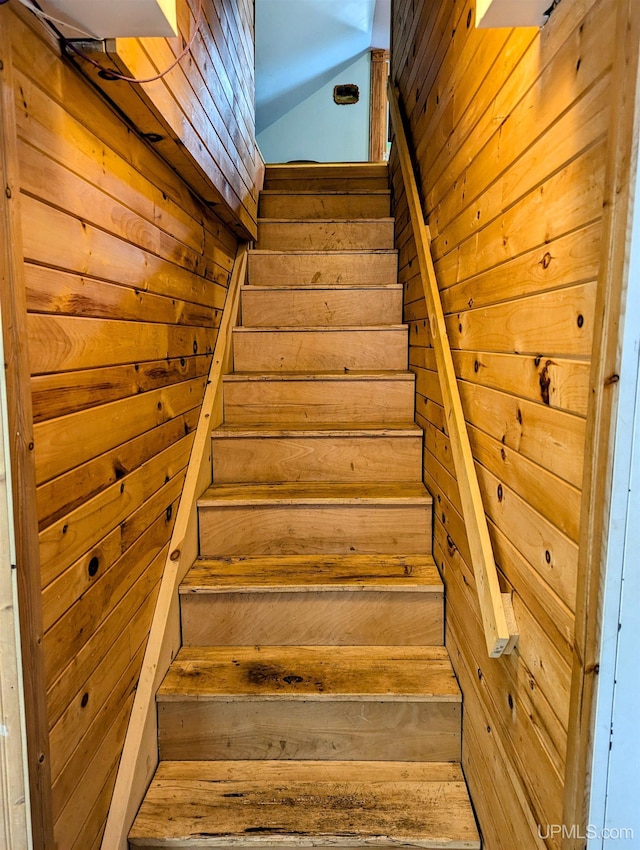 staircase featuring wooden walls