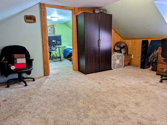 carpeted office featuring wood walls and vaulted ceiling