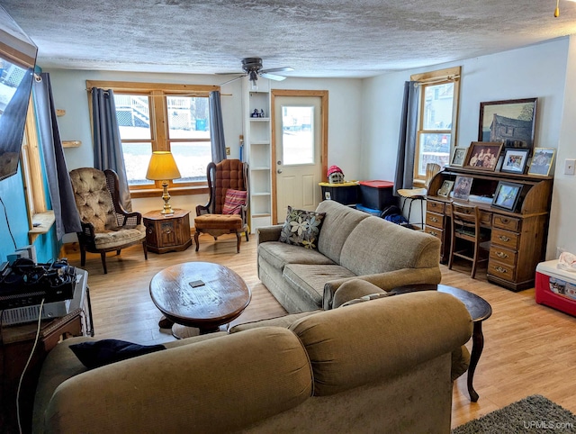 living room featuring a textured ceiling, light wood-type flooring, and ceiling fan