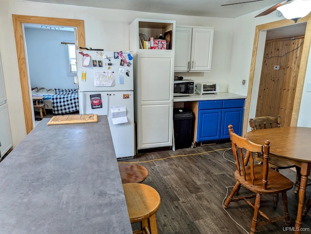 kitchen featuring blue cabinetry, ceiling fan, dark wood-type flooring, white fridge, and white cabinets