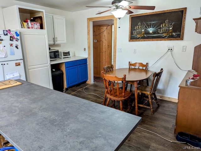 kitchen with white cabinets, white refrigerator, blue cabinets, and dark wood-type flooring