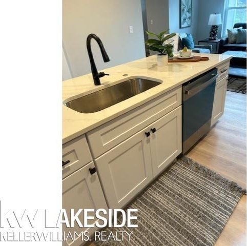 kitchen with dishwashing machine, sink, light stone counters, and white cabinetry