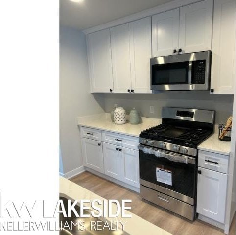 kitchen with white cabinetry, appliances with stainless steel finishes, and light hardwood / wood-style floors