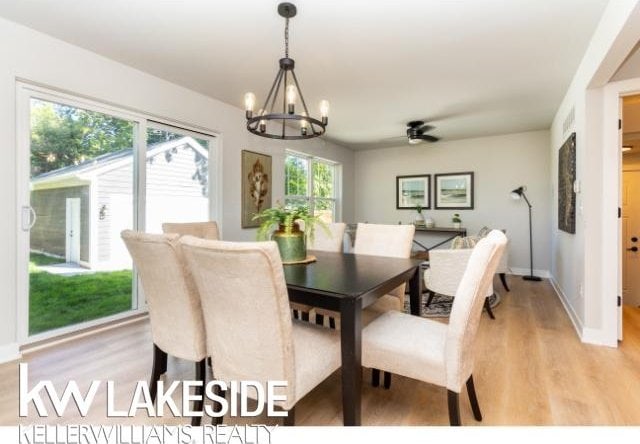 dining space with a healthy amount of sunlight, ceiling fan with notable chandelier, and light wood-type flooring