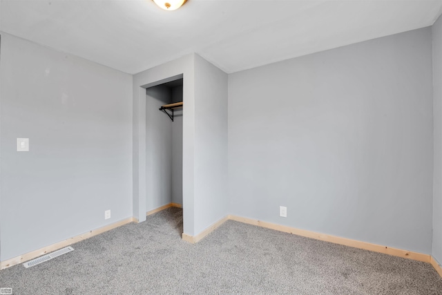 unfurnished bedroom with light colored carpet and a closet