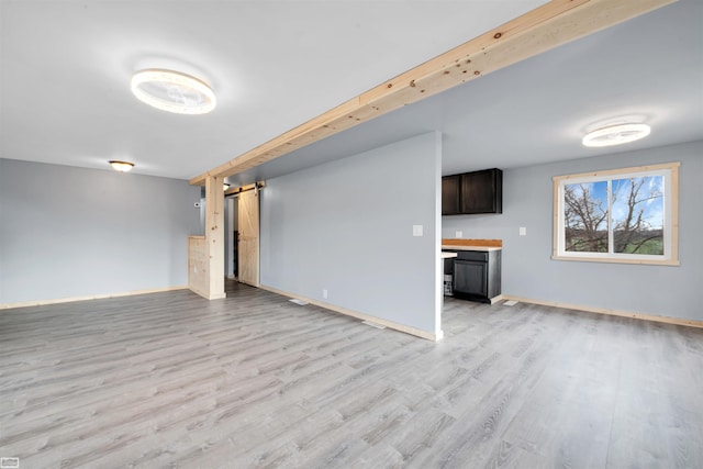 unfurnished living room featuring a barn door and light hardwood / wood-style floors