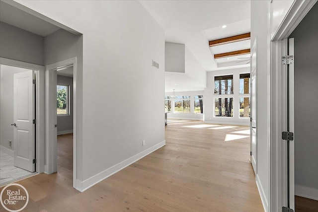 hall featuring beam ceiling, light wood-type flooring, and a notable chandelier