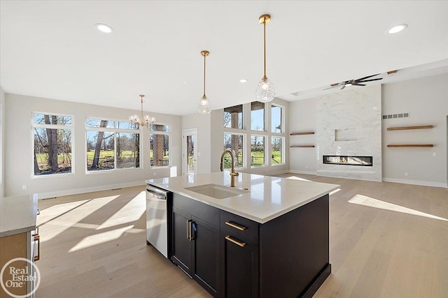 kitchen with a high end fireplace, a kitchen island with sink, sink, and a wealth of natural light