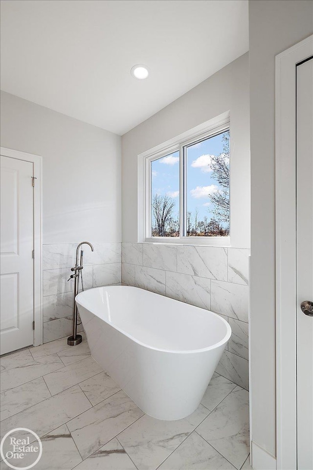 bathroom featuring a tub to relax in and tile walls