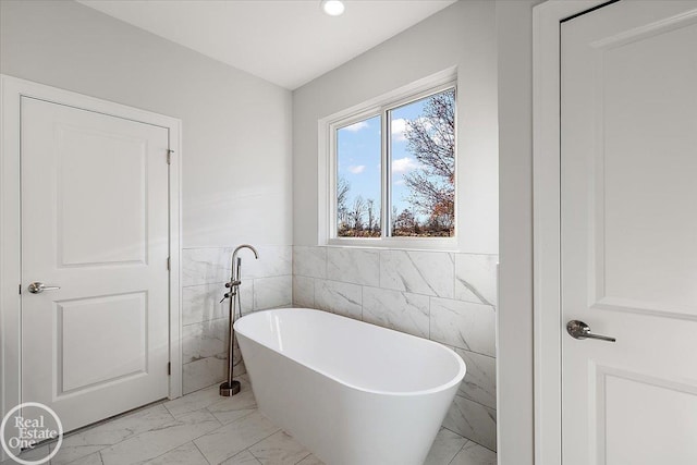 bathroom featuring a washtub and tile walls