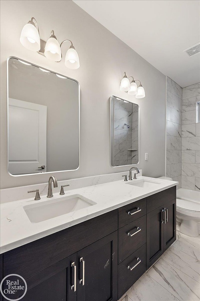 bathroom featuring tiled shower, vanity, and toilet