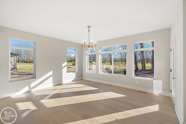 unfurnished dining area featuring light hardwood / wood-style flooring and an inviting chandelier