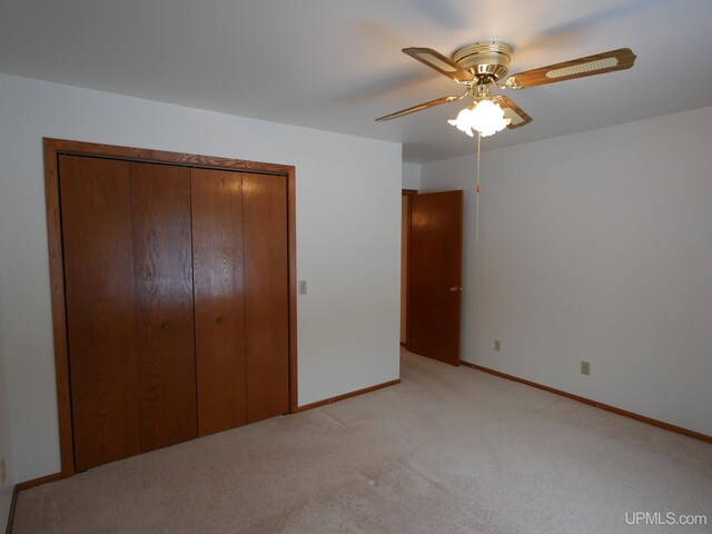 unfurnished bedroom featuring ceiling fan, a closet, and light carpet