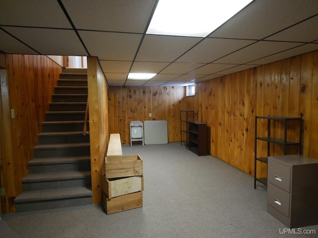 basement featuring a paneled ceiling and wooden walls