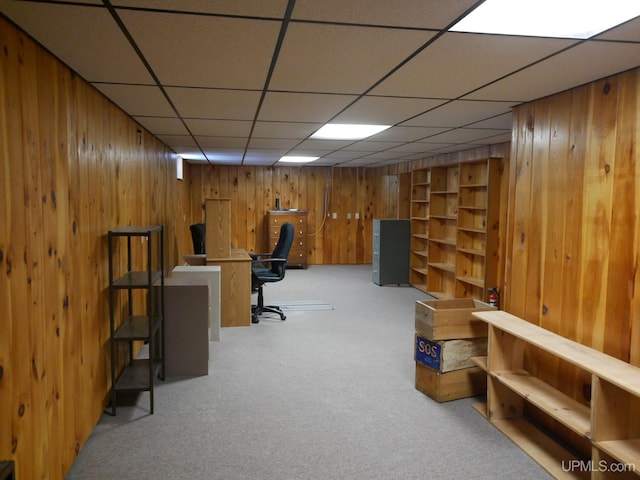 carpeted home office featuring a paneled ceiling and wooden walls