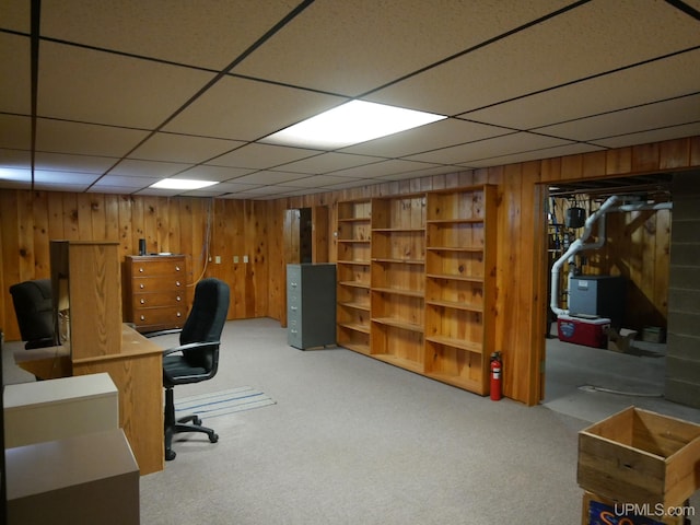 office space featuring carpet flooring, a paneled ceiling, and wooden walls