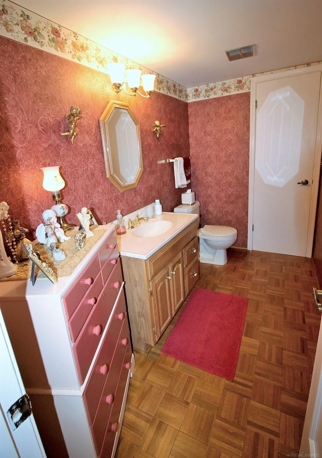 bathroom with vanity, toilet, and parquet floors