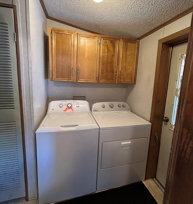 washroom with cabinets, a textured ceiling, washer and dryer, and crown molding