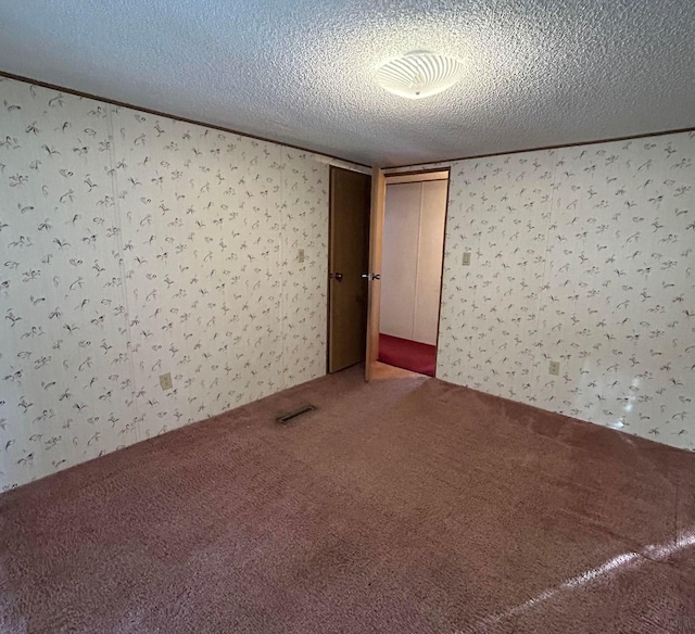 empty room with carpet and a textured ceiling