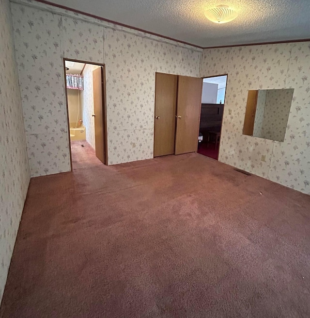 spare room with a textured ceiling, carpet floors, and crown molding