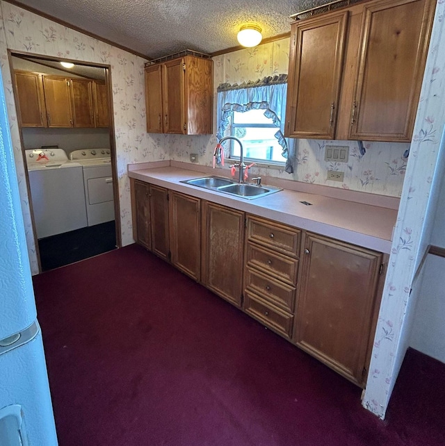 kitchen featuring washer and clothes dryer, dark carpet, crown molding, sink, and a textured ceiling