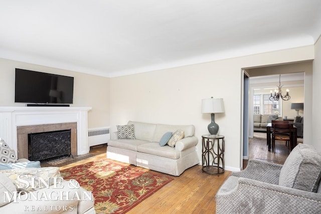 living room with hardwood / wood-style flooring, radiator heating unit, and an inviting chandelier