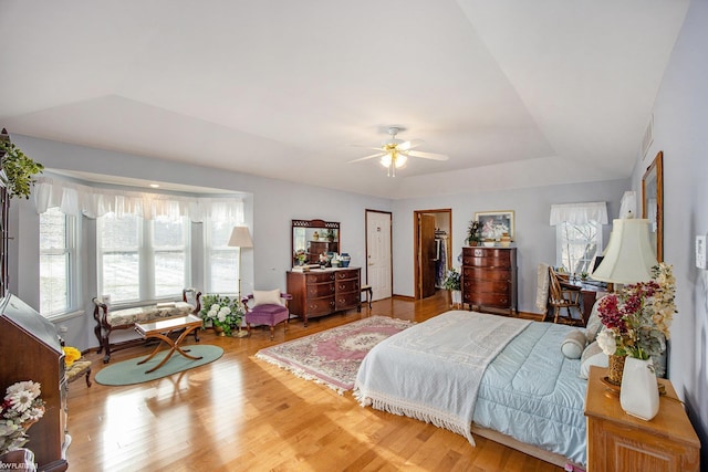 bedroom with hardwood / wood-style floors, a raised ceiling, and ceiling fan