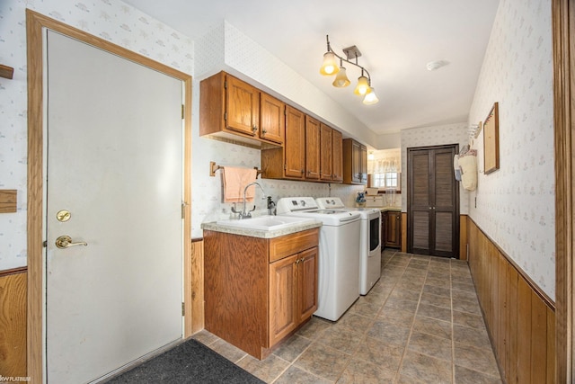 laundry room featuring wood walls, cabinets, independent washer and dryer, and sink