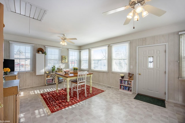 dining room featuring a wealth of natural light, wooden walls, and ceiling fan