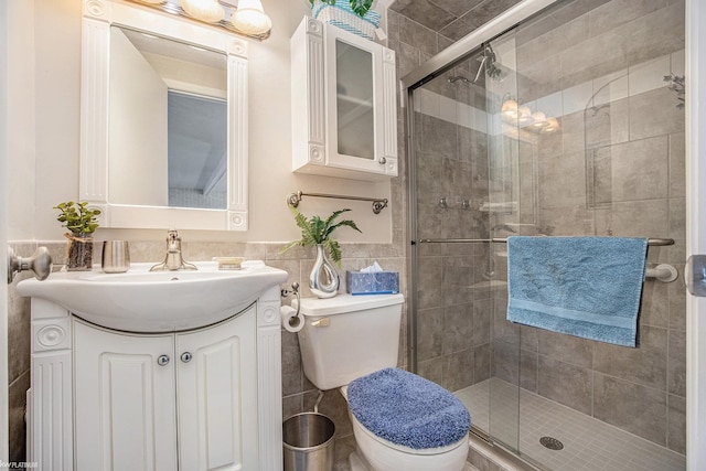 bathroom featuring walk in shower, vanity, toilet, and tile walls