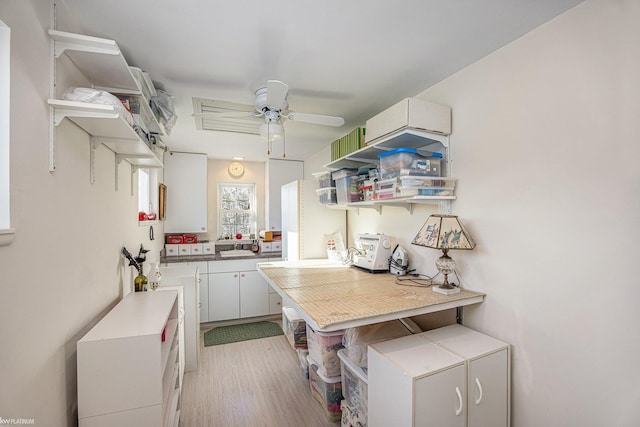 kitchen featuring white cabinets, ceiling fan, light wood-type flooring, and tile counters