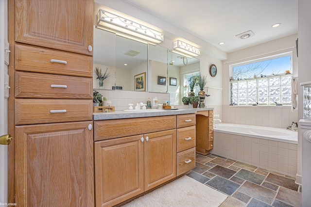 bathroom with a relaxing tiled tub and vanity