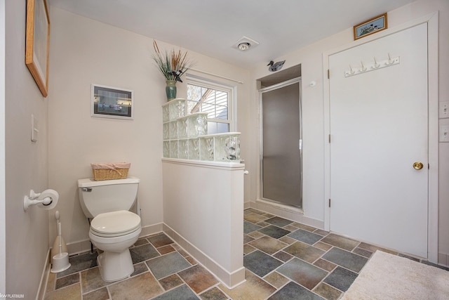 bathroom featuring toilet and a shower with shower door