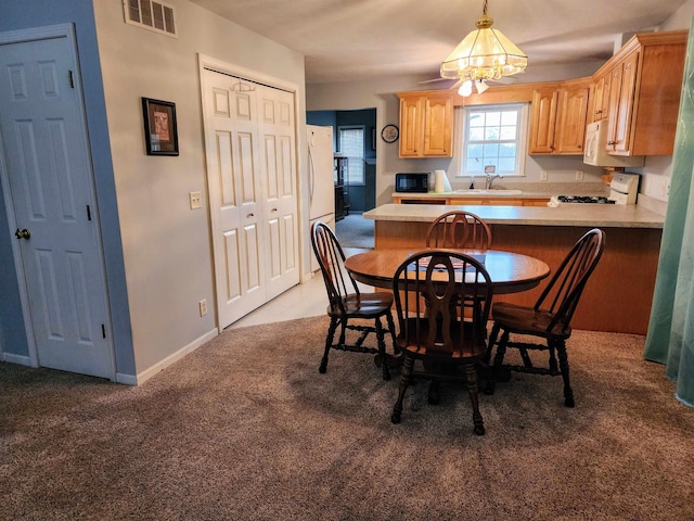 carpeted dining area featuring a chandelier and sink