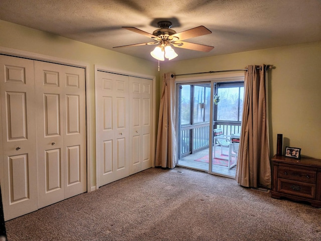 carpeted bedroom with a textured ceiling, ceiling fan, two closets, and access to outside