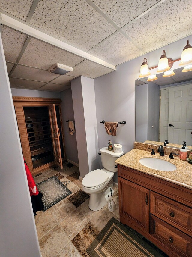 bathroom with a drop ceiling, toilet, and vanity