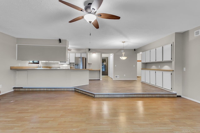 unfurnished living room with a textured ceiling, light hardwood / wood-style floors, and ceiling fan