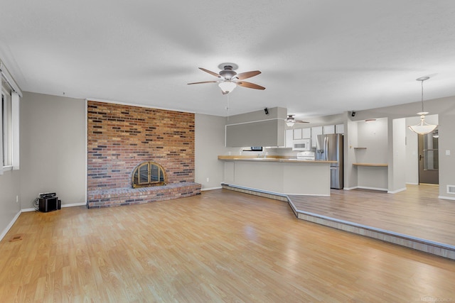 unfurnished living room featuring ceiling fan, a fireplace, and light hardwood / wood-style floors