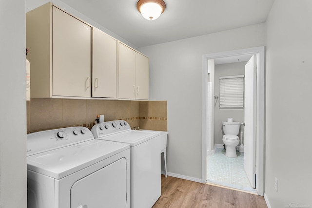 laundry area featuring light hardwood / wood-style floors, cabinets, and separate washer and dryer