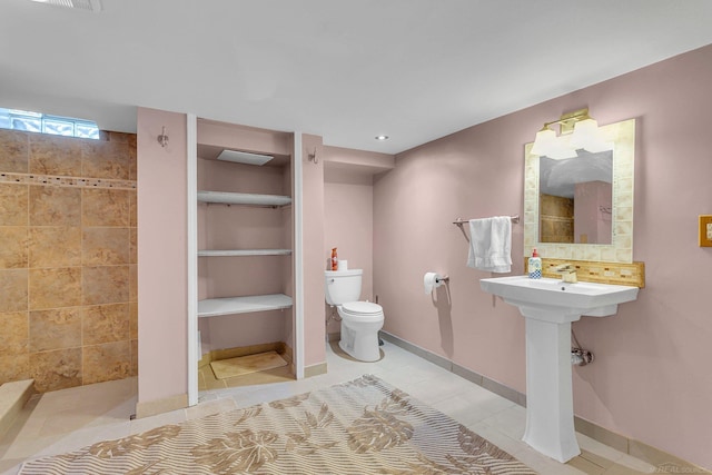 bathroom featuring toilet, tiled shower, and tile patterned floors