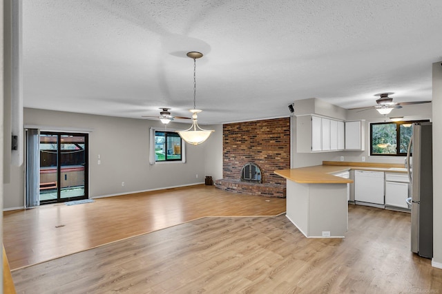 kitchen featuring dishwasher, hanging light fixtures, kitchen peninsula, light hardwood / wood-style floors, and white cabinets