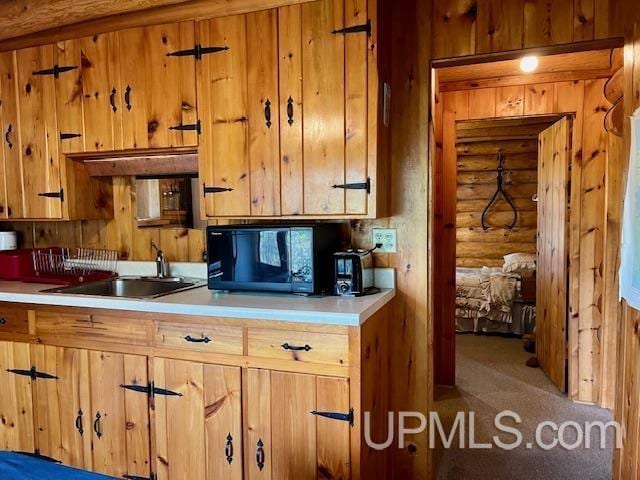 kitchen featuring carpet, sink, and log walls