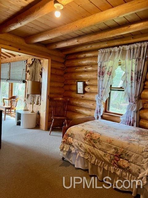 unfurnished bedroom with beamed ceiling, carpet floors, rustic walls, and wood ceiling