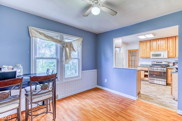 kitchen with light brown cabinetry, white appliances, light hardwood / wood-style flooring, and ceiling fan