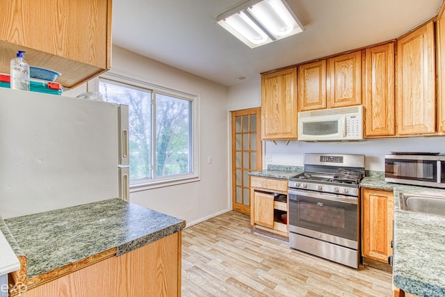 kitchen with light wood-type flooring, white appliances, and sink