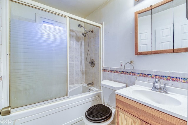 full bathroom with vanity, toilet, combined bath / shower with glass door, and tile walls