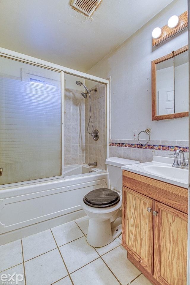 full bathroom with tile patterned floors, vanity, bath / shower combo with glass door, and toilet